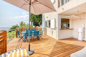 una terraza de madera con mesa, sillas y sombrilla en Villa Kap Grand Large, en Saint-Leu 41 fotos más
