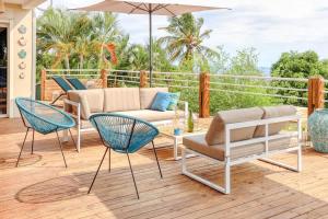 un patio con sofá, sillas y sombrilla en Villa Kap Grand Large, en Saint-Leu