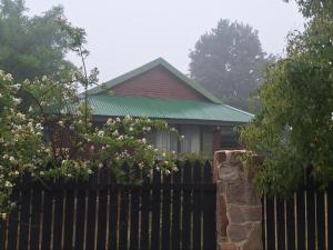 een huis met een hek ervoor bij Cinnamon & Sage Country Cabins in Dullstroom