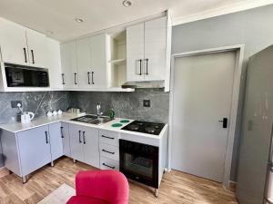 a kitchen with white cabinets and a red chair at 29 Windsor Flatlet 2 in Silver Sands