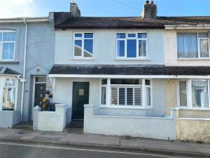 a white house with a blue door and windows at Drew Street Digs in Brixham