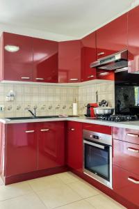 a red kitchen with red cabinets and appliances at Kaz Santa Maria in Saint-Leu +13 photos