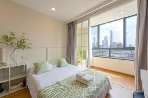 Shanghai Zighouse--The Bund Premium Apartment Suites في شانغهاي: غرفة نوم بها سرير ونافذة كبيرة