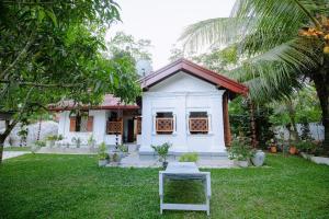 ein weißes Haus mit einem Stuhl im Hof in der Unterkunft Chali' Villa in Matale