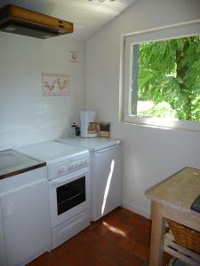 Il comprend une cuisine équipée d'une cuisinière blanche et d'une fenêtre. dans l'établissement La Maison du Sabotier, à Corancy