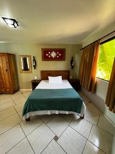 a bedroom with a bed with a green blanket at Pousada Recanto dos Cisnes in Betim