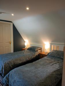 two beds in a room with two lamps on tables at The Grove Arms 