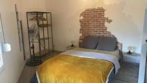 een slaapkamer met een bed met een bakstenen muur bij La Hestia à 2 pas du Château in Sedan