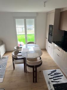 een keuken en eetkamer met een tafel en stoelen bij Chambre d'hôte, dans 4 pièces , avec terasse, jardin in Saint-Witz