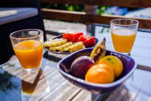 a bowl of fruit and two glasses of orange juice at Kaz Combava in Étang-Salé