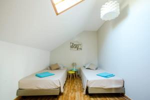 two beds in a room with white walls and wood floors at Kaz Combava in Étang-Salé +13 photos