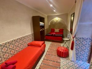 a bedroom with two beds and a red couch at Riad Prada in Marrakech