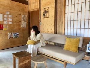 een vrouw op een bank in een kamer bij HANARE紡舎Tsumugiya in Ogawa
