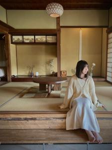 een vrouw op een bank in een kamer bij HANARE紡舎Tsumugiya in Ogawa