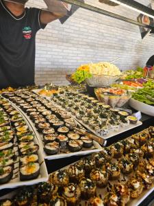 a man standing in front of a buffet of food at Pak Suítes Hotel in Luis Eduardo Magalhaes
