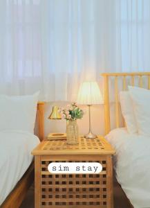 ein Schlafzimmer mit einem Tisch, auf dem eine Lampe und Blumen stehen in der Unterkunft Sim stay심스테이-매일 침구세탁clean bed in Mŏnnae