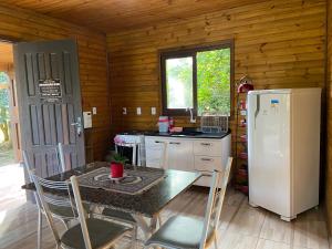 a kitchen with a table and a refrigerator at CHALÉS DO VÔ LÉRIO/TORRES-RS in Torres