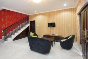 a living room with two chairs and a desk and a television at Hotel O near UGM formerly Bayang Brothers Guest House in Yogyakarta