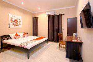 a bedroom with a bed and a desk and a television at Hotel O near UGM formerly Bayang Brothers Guest House in Yogyakarta