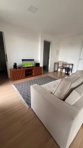 a living room with a white couch and a television at SouMais Icaraí, Varanda dos Sonhos in Niterói +8 photos