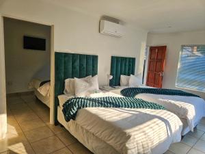 deux lits dans une chambre avec des têtes de lit vertes dans l'établissement The M GuestHouse, à Kempton Park