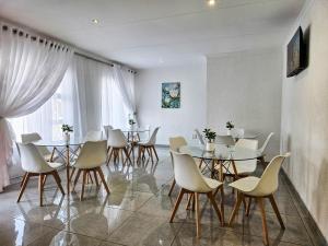 une salle à manger avec des tables et des chaises blanches dans l'établissement The M GuestHouse, à Kempton Park