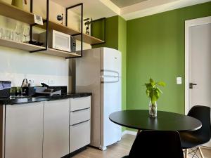 a kitchen with green walls and a table and a refrigerator at Aptos 1 ou 2 quartos no Centro com Piscina e Academia in Maringá