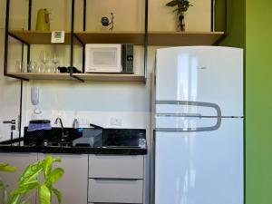 a kitchen with a white refrigerator and a microwave at Aptos 1 ou 2 quartos no Centro com Piscina e Academia in Maringá
