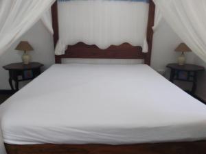 Un dormitorio con una cama blanca con dos mesitas de noche. en Allison Homes, en Kilifi 19 fotos más