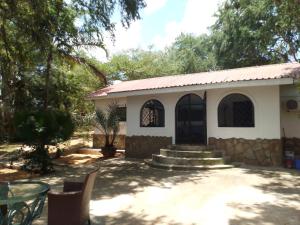 un pequeño edificio blanco con mesa y sillas en Allison Homes, en Kilifi