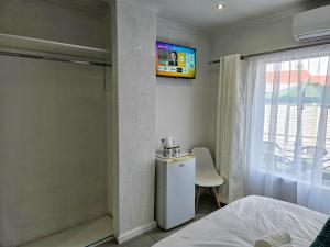une chambre avec un lit et une télévision au mur dans l'établissement The M GuestHouse, à Kempton Park