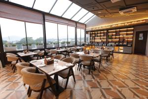 a restaurant with tables and chairs and large windows at Hotel Ganga Sutra in Haridwār