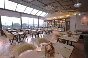 un restaurante con mesas, sillas y ventanas en Hotel Ganga Sutra, en Dehradun 32 fotos más