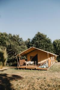a large wooden house with a table in a field at Lodge La Forêt in Saint-Sauveur