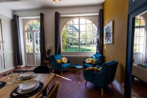 a living room with a table and chairs and windows at Au p'tit tcheste in Hontanx