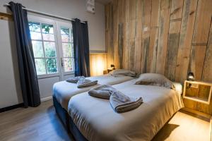 two beds in a room with wooden walls at Au p'tit tcheste in Hontanx +65 photos