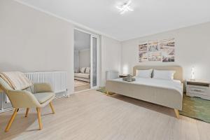 una camera da letto bianca con un letto e una sedia di Casa Albă a Roman