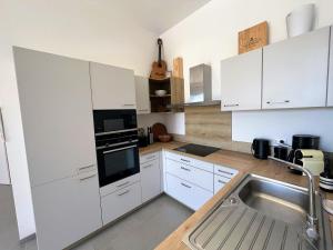 a kitchen with white cabinets and a sink at Bel appartement avec piscine en bord de mer in Ajaccio