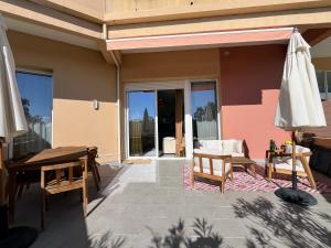 a patio with a table and chairs and an umbrella at Bel appartement avec piscine en bord de mer in Ajaccio