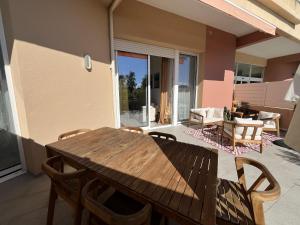 a wooden table and chairs on a patio at Bel appartement avec piscine en bord de mer in Ajaccio +20 photos