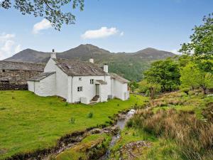 an old cottage on a hill with mountains in the background at 4 Bed in Buttermere SZ090 in Buttermere