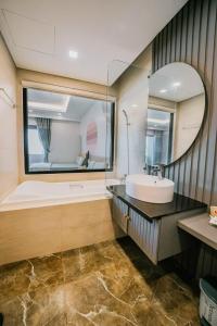 a bathroom with a tub and a sink and a mirror at FLC Sea Tower - Sea view Quy Nhơn in Quy Nhon