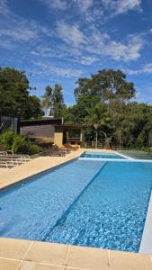 a large blue swimming pool with chairs around it at Tupa Lodge in Puerto Iguazú +42 photos