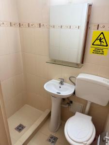 een badkamer met een wastafel, een toilet en een spiegel bij Hotel Nadia Eforie Nord in Eforie Nord