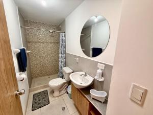 a bathroom with a sink and a toilet and a mirror at Ideal para familia de 5 in Ibarra +18 photos
