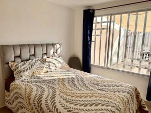 a bed with a comforter and a window in a bedroom at Ideal para familia de 5 in Ibarra