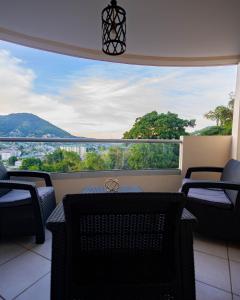 a balcony with chairs and a large window with a view at 3 Bdr Apartment close to Port of Spain in Diego Martin