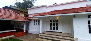 a white house with red roofs and a porch at Heaven Cloud Stay Hub Attappadi in Attappādi +20 photos