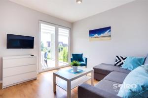 a living room with a couch and a tv at SOLEO Family Resort - domki 3 min od Morza - 3 Baseny, 3 Jacuzzi, Sauna, ANIMACJE, Małpi Gaj, 3 Sale Zabaw, 4 Place Zabaw, 2 Restauracje in Rewal