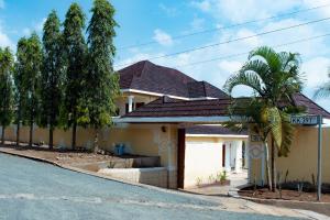 a house with a palm tree next to a street at Elegant Villa Apart in Kigali